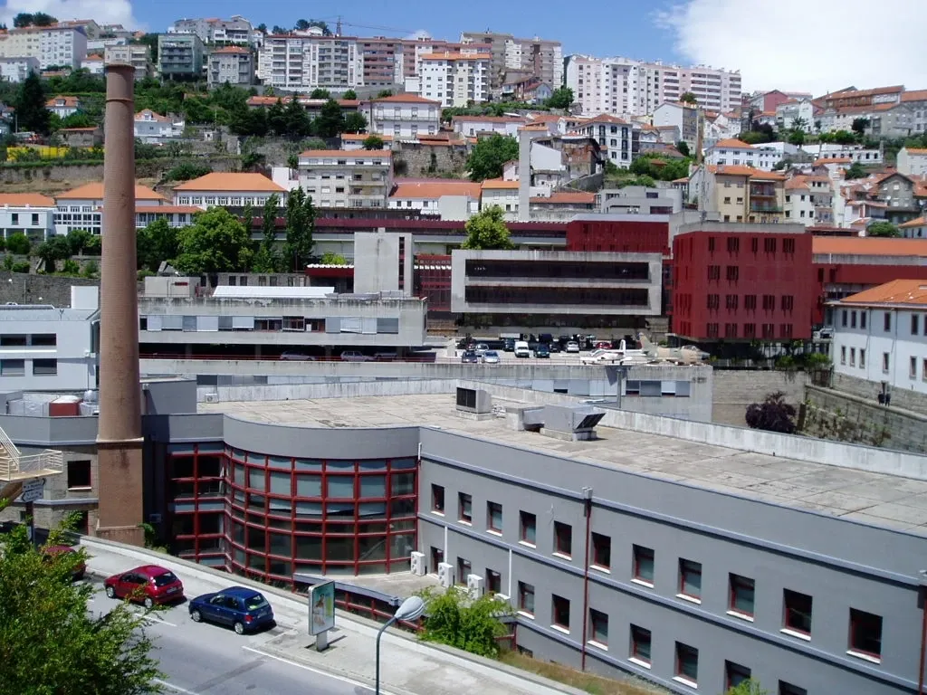 Edifícios da UBI junto a uma antiga chaminé de tijolo, com a Covilhã na encosta ao fundo.